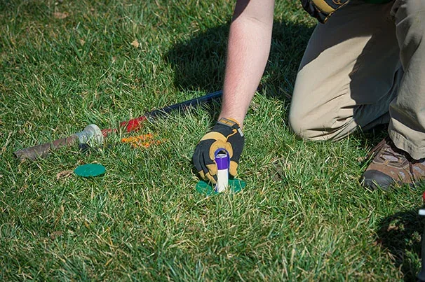 EnviroCare technician installing a Sentricon termite bait station in a customer's lawn